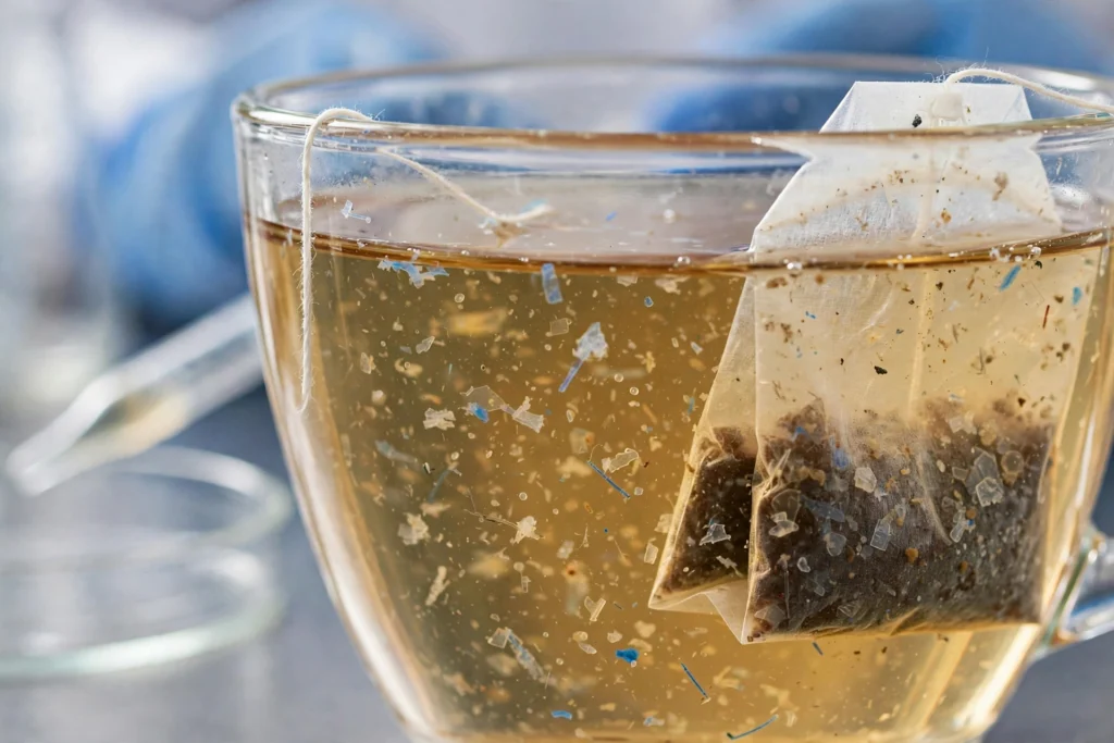 Cup of tea with plastic tea bag and magnified microplastic particles
