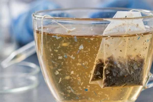 Cup of tea with plastic tea bag and magnified microplastic particles