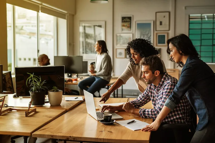A small team working together around a laptop in an office