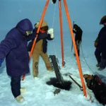 Researchers collecting a water sample with a Niskin bottle at sea