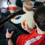 Friends playing video games at home while sitting on a sofa