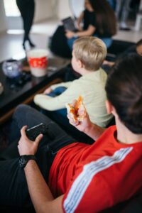 Friends playing video games at home while sitting on a sofa